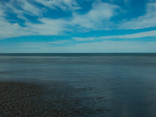 Playa solitaria con conchillas, agua clara y cielo nublado