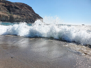 waves on the beach. waves crash on the rocky sandy shore of the ocean.  Mountains and ocean