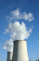 Close up picture of smoking chimneys against blue sky.