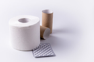 A roll of toilet paper with a package of white pills on a white background.
