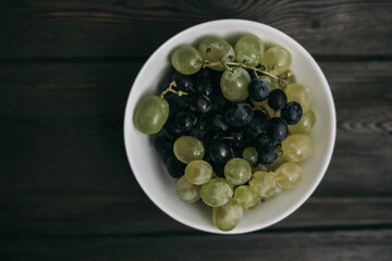 grapes in a plate on a wooden table top view fruits