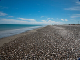 Playa solitaria con conchillas, agua clara y cielo nublado