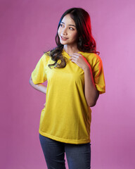 Young female model wearing blank T-shirt in studio background. Woman in cheerful pose with blue and red lighting. Modern shirt mockup. Young women are stylish like adult models. Pretty sheer makeup.