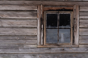 The facade of an old wooden log building with a small window
