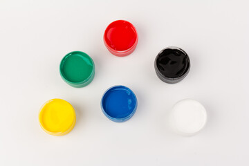 Plastic jars with paint of different colors for children's creativity on white background. Paint bottles for art