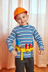 The boy is in a good mood with a toy helmet and tools.