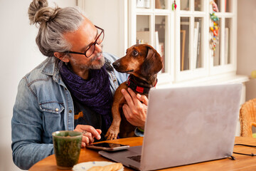 Man at home office with cute dachshund dog sitting close together