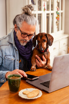 Man at home office with cute dachshund dog sitting close together