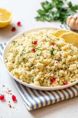 Cooked couscous in a ceramic plate on a white concrete background close-up. Maghreb cuisine, vegan food.