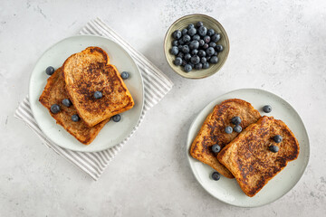 View from above of two plates with french toast with blueberries on a grey background, from above, minimalistic style
