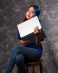 Beautiful young woman, charming business CEO holding notebook wearing blank t-shirt while stylish isolated background. Portrait of a happy and excited woman with a laptop. Models for new notebook.