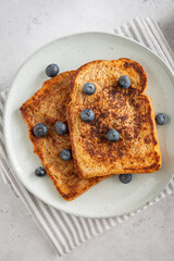 Close-up from above of two slices of french toast with blueberries on a plate on grey background, fresh clean style
