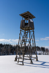 white fluffy snow and on it stands a large hunting tower built of wood