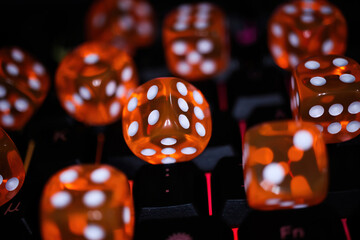 Makro closeup of group isolated red shiny dice cubes with on illuminated computer keyboard -...