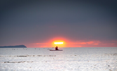 Silhouette of the girl on a surfboard at sunset