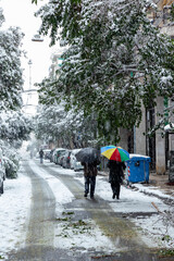 Obraz premium Unidentified couple walking down the street during snowstorm in Athens city, capital of Greece, Europe