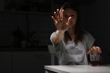 Depressed sad young woman feeling bad drinking whiskey alone at home, showing hand stop alcohol, alcoholic suffering from alcohol dependence having problems, alcoholism concept.