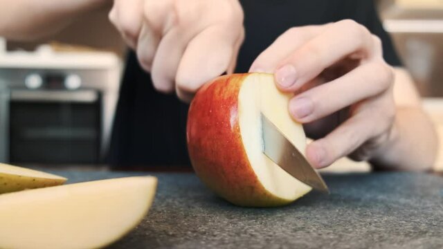 A man slicing an apple on a cooking board using a knife