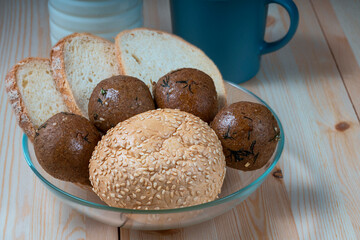 fresh delicious buns and slices of wheat bread on wooden kitchen table