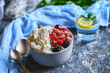 Recipe ideas for summer diet breakfast, healthy morning dessert in portioned soup plate with summer berries - raspberry, cherries, blackberry. On stone background.