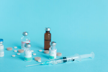 Medical ampoule, syringe and pills isolated on blue background