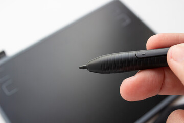A person draws on a graphics tablet. The hand holds the touch pen. Wired graphic tablet for...