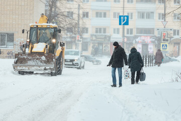 Fototapeta premium a man with difficulty walks through deep snow, snowdrifts on the sidewalk after a heavy snowfall. poor operation of public utilities in winter