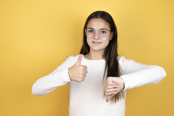 Beautiful child girl wearing casual clothes Doing thumbs up and down, disagreement and agreement expression. Crazy conflict