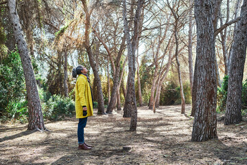 Woman looks up to take photos with analog reflex camera in forest