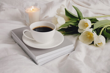 Obraz na płótnie Canvas Coffee, candle and white tulips on bed.