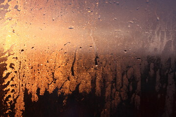 Frozen drops of condensation on a transparent glass window in the winter season with natural sunlight through the glass, high humidity, temperature difference, natural background