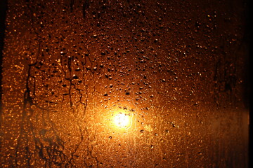 Window transparent glass with condensation, high humidity in the room, large drops of water flow down, warm tone, natural drops