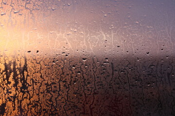 Window transparent glass with condensation, high humidity in the room, large drops of water flow down, warm tone, natural drops
