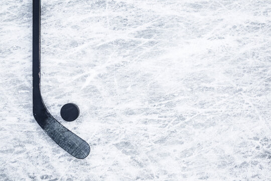 Black hockey stick and rubber puck on ice background. Closeup. Empty place for text. Top down view.