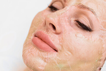 Fototapeta premium Enzyme mask in the process of drying on a woman's face close-up. Rejuvenation and facelift in cosmetology