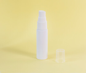 Studio shot of white spray plastic bottle isolated on yellow background. Clipping path included. Ready for your design.