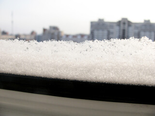 Frozen white snow on a modern plastic window frame
