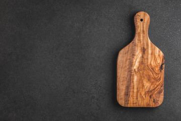 Cutting board on black textured table. View from above.	
