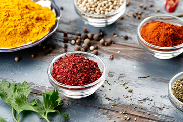 Various spices in bowls on grey table. Paprika, turmeric, red pepper, cumin, coriander. Powdered spices