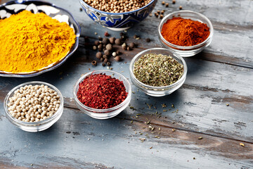 Various spices in bowls on grey table. Paprika, turmeric, red pepper, cumin, coriander. Powdered...