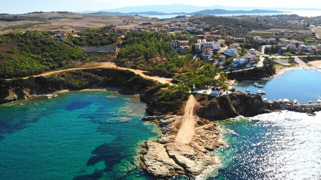 Aerial drone view of the Nea Roda situated on the Aegean sea coast, Greece. Multiple buildings with greenery, church near the shore