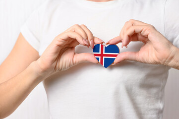 Love Iceland. The girl holds a heart in the form of the flag of Iceland on her chest. Icelandic concept of patriotism