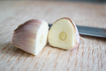Ajo cortado a la mitad sobre tabla de madera y cuchillo atrás