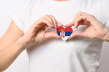 Love Serbia. A girl holds a heart in the form of the flag of Serbia on her chest. Serbian concept of patriotism