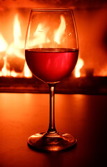 Close-up of a glass of white wine in the backlight of a burning fireplace.