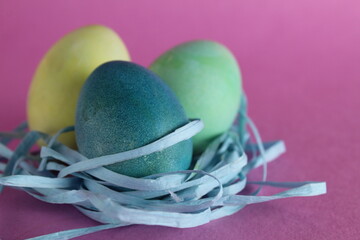Easter background three multicolored eggs are candy next to a pink background with room for text copyspace