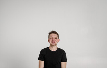 
teen guy looking at camera
 and sincerely smiling with teeth on a white background in a black T-shirt