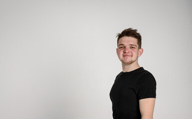 teen guy looking at the camera smiling with kind eyes on a white background in a black t-shirt

