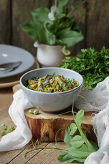 Vegan protein meal, dish of  stewed green legume vegetables: peas, green bean, broccoli garnished with parsley and flower petals, closep, overhead top down view, healthy vegan food concept