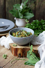 Vegan protein meal, dish of  stewed green legume vegetables: peas, green bean, broccoli garnished with parsley and flower petals, closep, overhead top down view, healthy vegan food concept